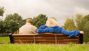 Two people sitting on a bench in a field