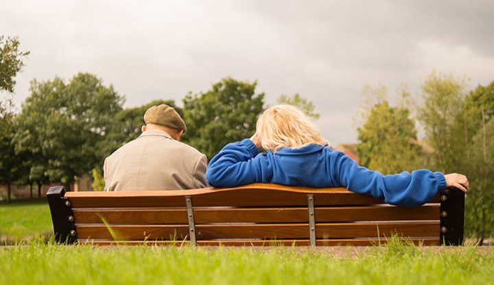 Two people sitting on a bench in a field