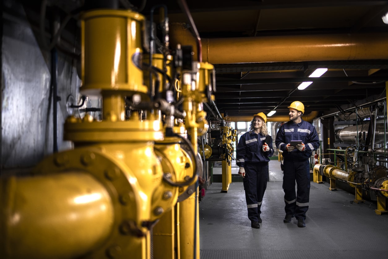 Man and woman walking through oil and gas facility